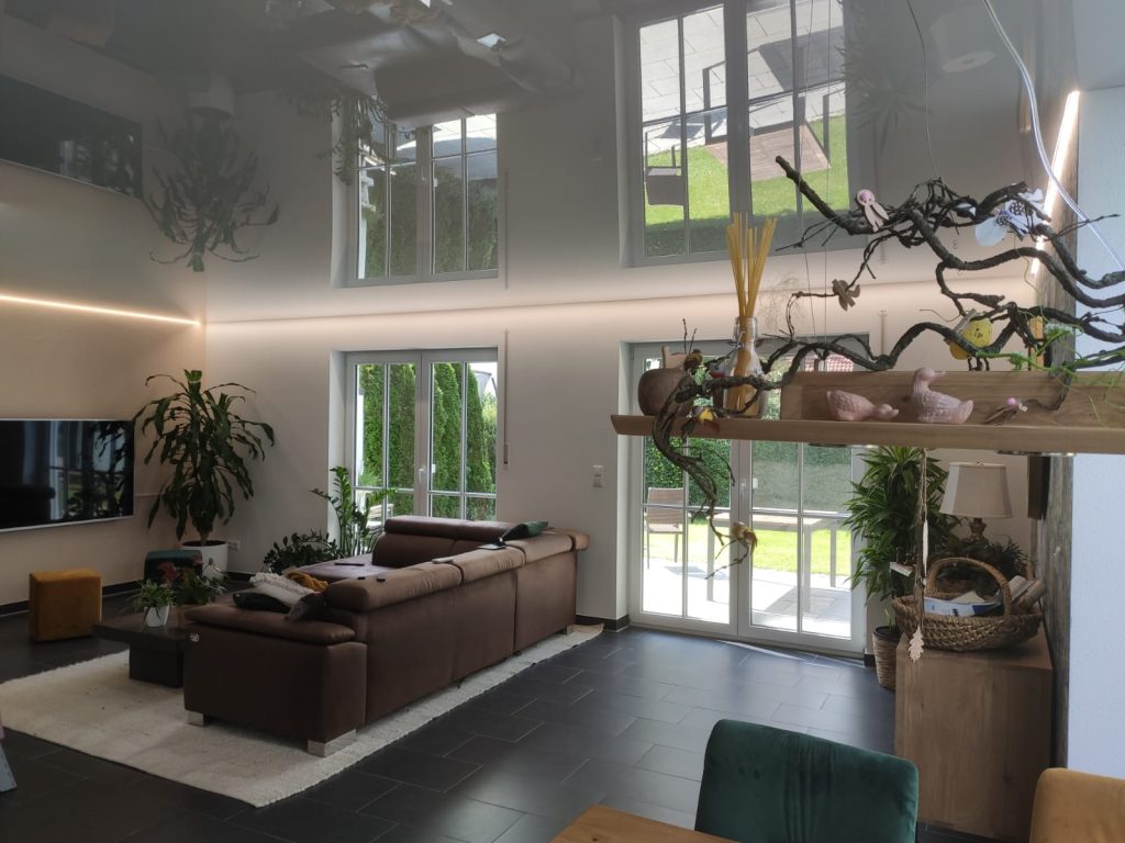 Moderne Glanz Spanndecke im Wohnzimmer mit integrierter LED-Lichtlinie und reflektierender Oberfläche