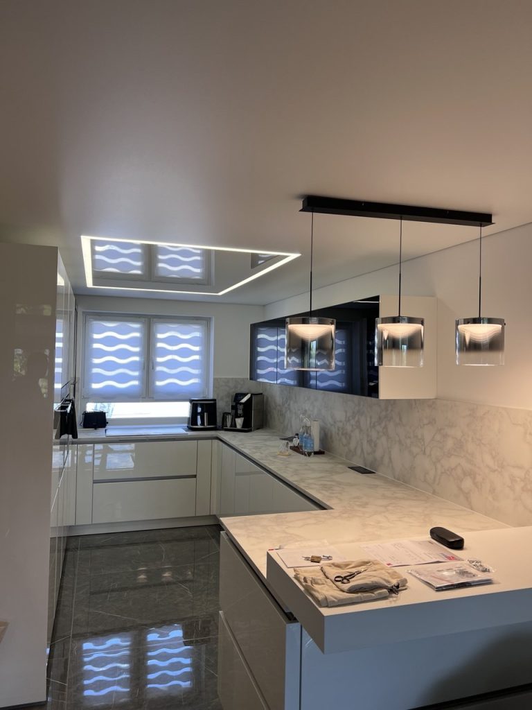 Moderne Küche mit Spanndecke, LED-Lichtlinie und Pendelleuchten über der Arbeitsfläche