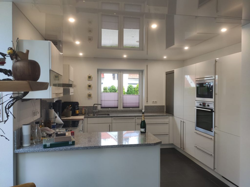 Moderne Küche mit weißer Lackspanndecke, LED-Spots und Kochinsel